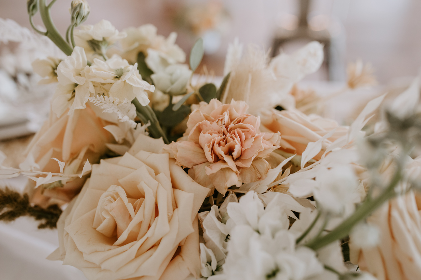 a bouquet of white and peach flowers on a table