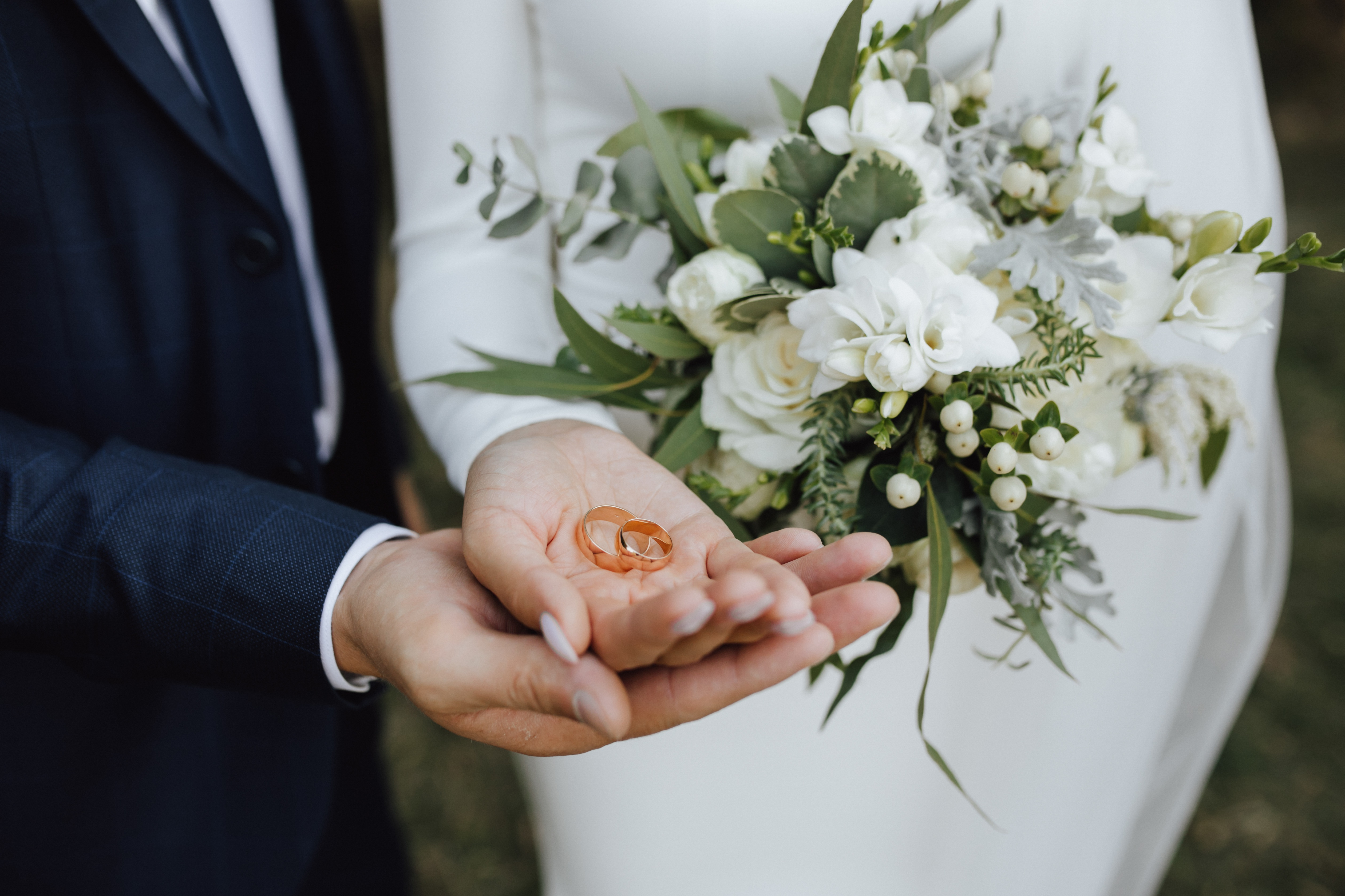 a close up of the hands of a bride and groom with wedding rings 